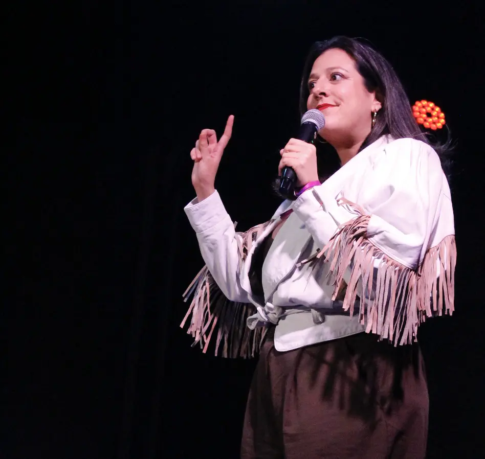 María A Secas sonriendo con un micrófono durante una presentación